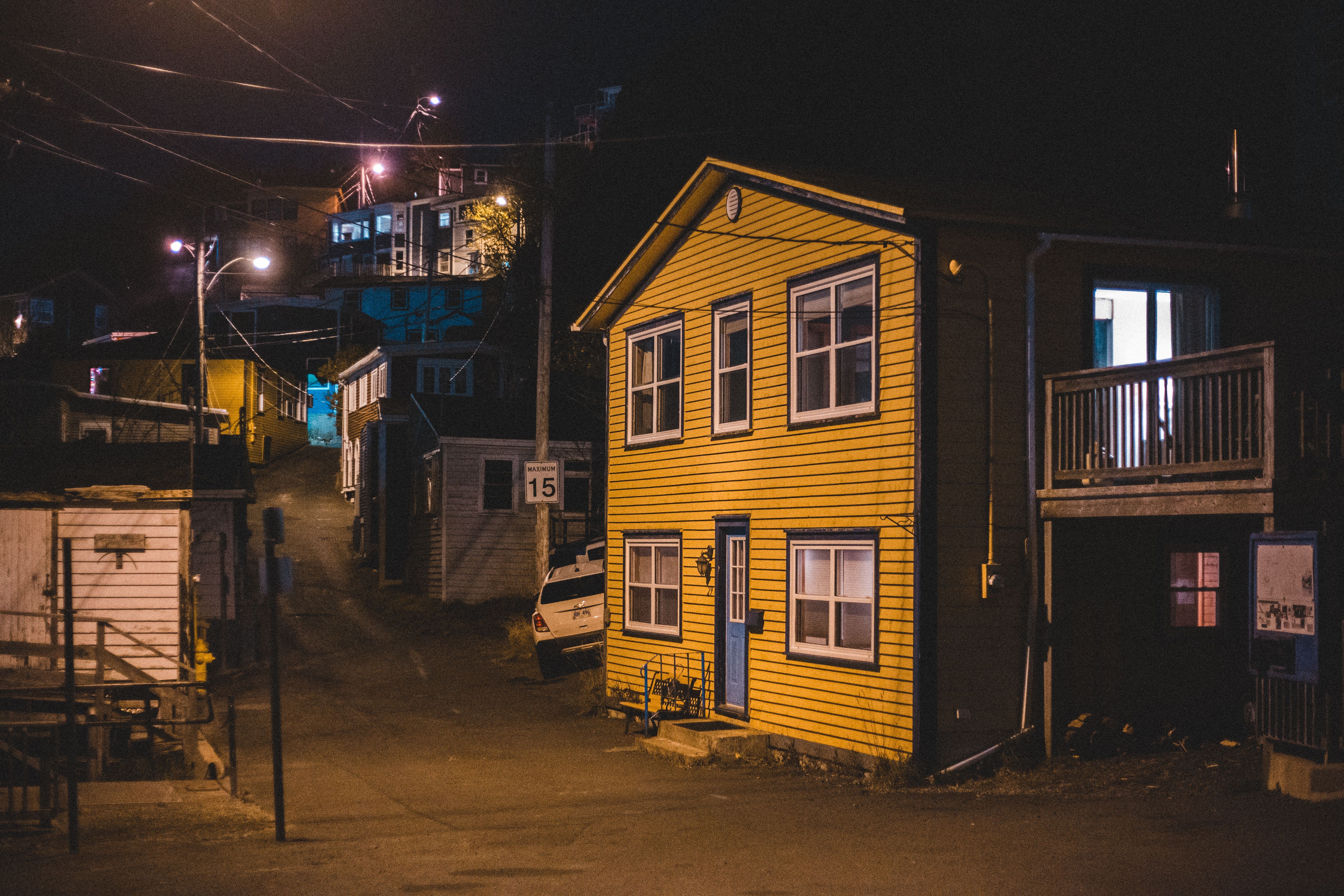 A quiet suburban street at night with illuminated houses and glowing streetlamps, the kind of neighborhood setting where quiet hours matter.