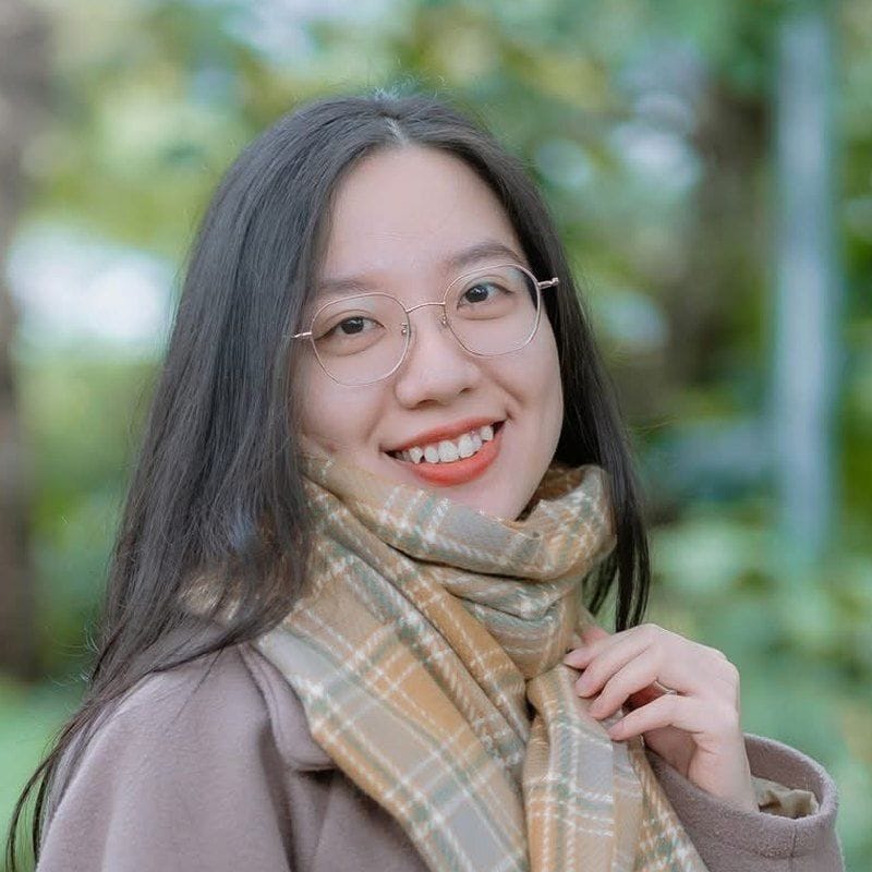 Cina, smiling, in glasses and a plaid scarf